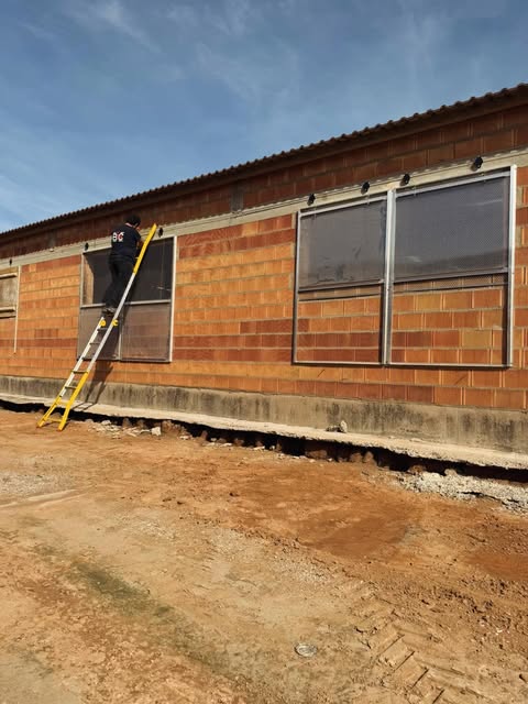 Operario de Caballe Mantenimiento trabajando en las ventanas de una nave ganadera